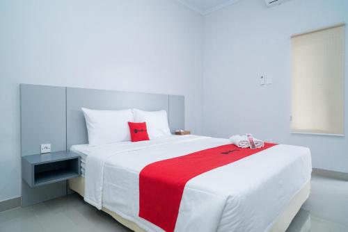a bedroom with a large white bed with a red blanket at RedDoorz @ Jalan Gunung Talang Mahendradatta in Kerobokan