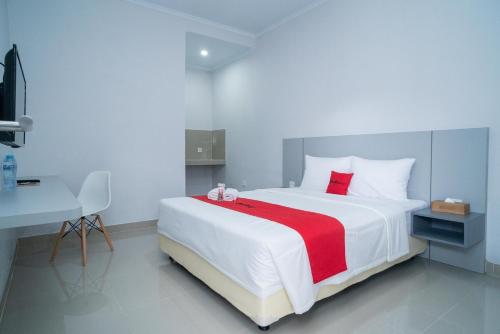 a bedroom with a large white bed with a red blanket at RedDoorz @ Jalan Gunung Talang Mahendradatta in Kerobokan