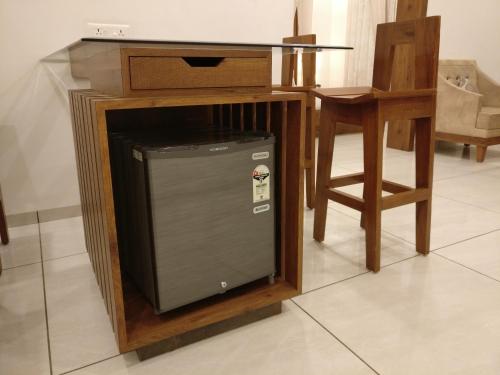 a small refrigerator in a wooden stand next to a table at Hotel Kalyan's - Mansingh Inn in Khambhāliya