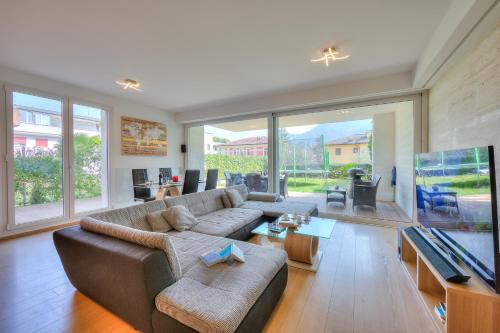 sala de estar con sofá y ventana grande en Rebecca Garden - Happy Rentals en Lugano