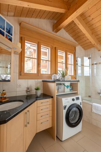 a kitchen with a washing machine and a sink at Königin der Alpen in Beatenberg