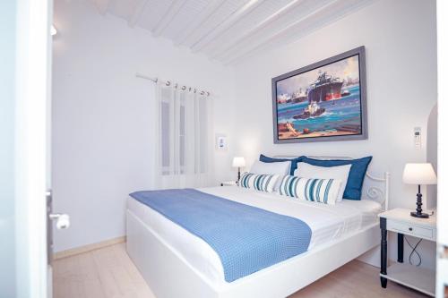 a white bedroom with a large bed with blue pillows at Like a white seagull in Mykonos! in Mýkonos City