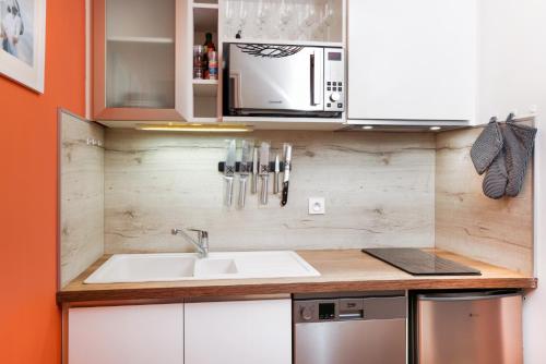 une cuisine avec un évier et un micro-ondes dans l'établissement Le Cocon de la Cité - Parking au Pied de La Cité, à Carcassonne
