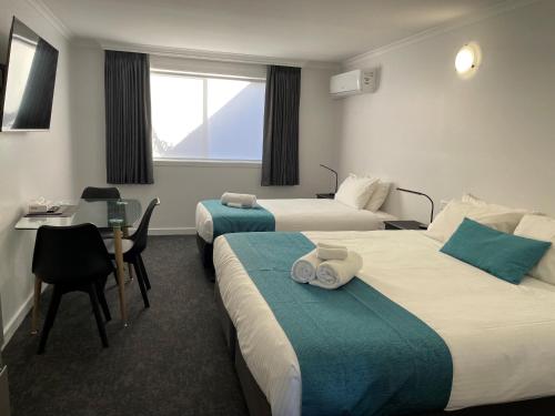 een hotelkamer met 2 bedden en een bureau bij Barham Bridge Motor Inn in Barham