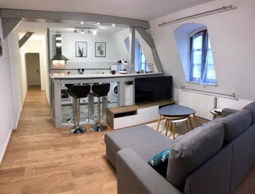 een woonkamer met een bank en een bar bij La Tour de Jeanne : Hypercentre charme et design in Rouen