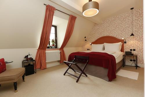 a bedroom with a bed with a red blanket and a chair at Burg Reichenstein in Trechtingshausen