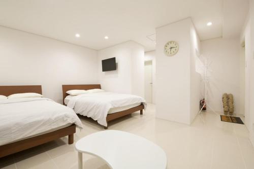 um quarto com duas camas e um relógio na parede em プロスパービル3b em Kume