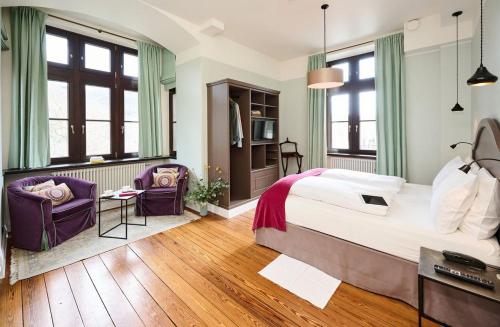 a bedroom with a large bed and two purple chairs at Burg Reichenstein in Trechtingshausen