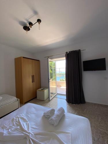 a bedroom with a white bed and a sliding glass door at Seafront Rooms - Private Beach Access in Sarandë