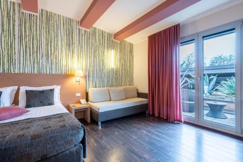 a bedroom with a bed and a couch and a window at Relais Bellaria Hotel & Congressi in Bologna