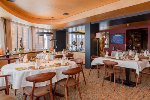 a restaurant with white tables and chairs and windows at Wohlfühlhotel Hubertushof in Stuben am Arlberg