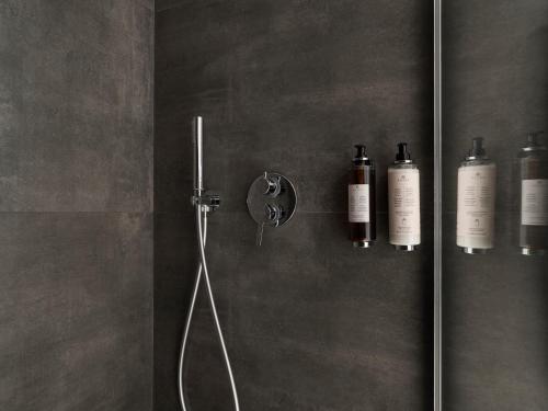 a bathroom with a shower with three bottles on the wall at Savoia Rooms Roma in Rome