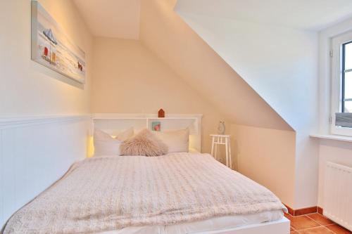 ein Schlafzimmer mit einem weißen Bett im Dachgeschoss in der Unterkunft Haus am Falkenweg Haus am Falkenweg Appartement 6 in Scharbeutz