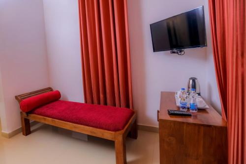 um quarto com um banco vermelho e uma televisão na parede em Sigiri Asna Nature Resort em Sigiriya