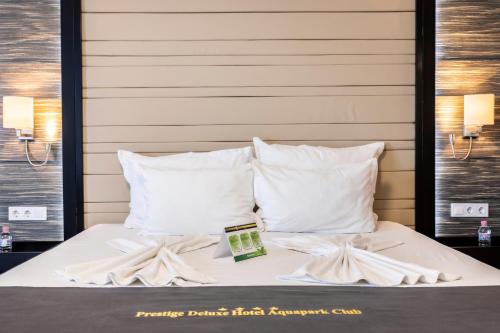 a bed with white pillows and a book on it at Prestige Deluxe Hotel Aquapark Club - All inclusive in Golden Sands