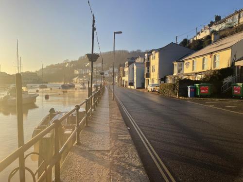 a street next to a river with houses and a fence at Little Mainstone Guest House in Looe