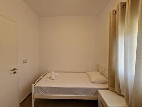 a small white room with a bed and a window at Hotel Queen Margaret Seaside in Ksamil