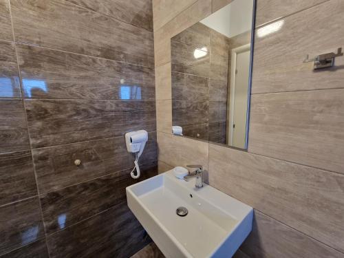 a bathroom with a sink and a mirror at Hotel Queen Margaret Seaside in Ksamil