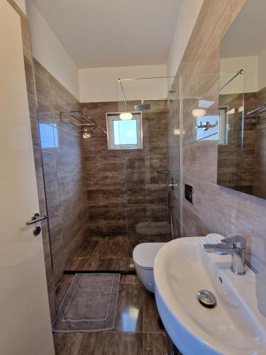 a bathroom with a toilet and a sink and a shower at Hotel Queen Margaret Seaside in Ksamil