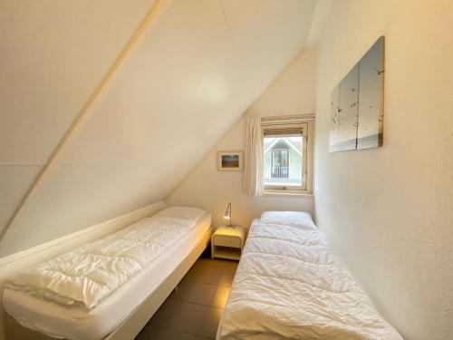 Un dormitorio pequeño con una cama y una ventana. en Previnaireweg 22, en Callantsoog