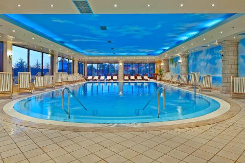 a large swimming pool in a hotel lobby with chairs at Hotel Picok in Ðurđevac