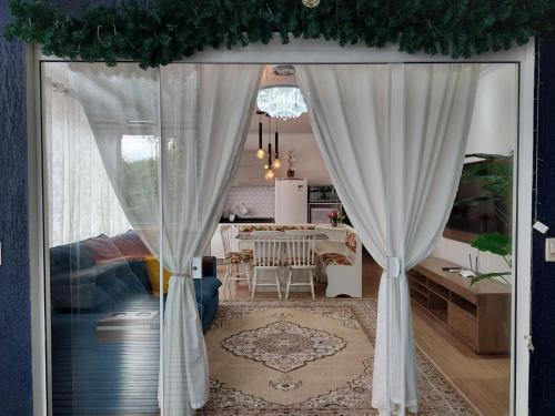 uma porta aberta para uma sala de estar com cortinas brancas em Casa em Gramado em Gramado