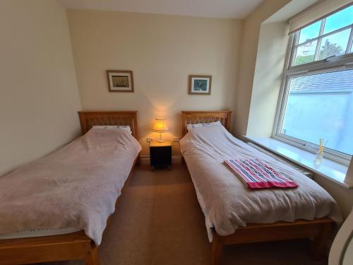 two twin beds in a room with a window at Upper Tresulian in Saint Mawes