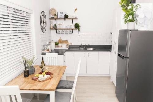 a kitchen with a wooden table and a refrigerator at Rustling Oaks NZ Boho Pool House in Cambridge