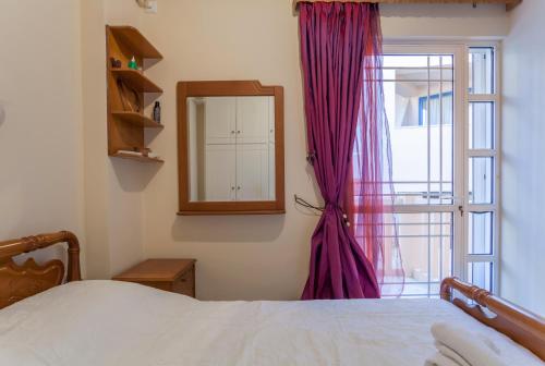 1 dormitorio con cama, espejo y ventana en CHRISTINE SEASIDE APARTMENTS IN CHANIA en Stalos