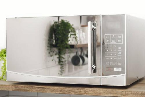 a silver microwave oven sitting on a counter at Rustling Oaks NZ Boho Pool House in Cambridge