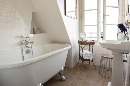 a white bathroom with a tub and a sink at Hotel Le Petit Chomel in Paris