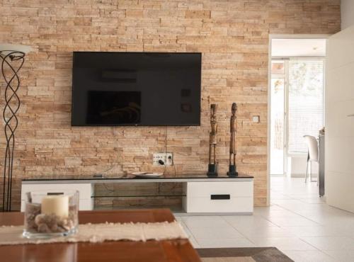 een woonkamer met een tv aan een bakstenen muur bij Villa en Cala Vadella Familias y Parejas in San Jose de sa Talaia