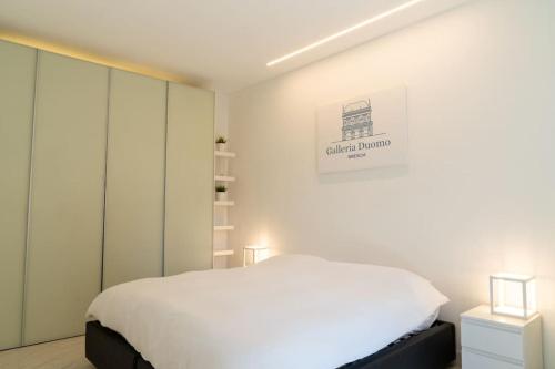 a white bedroom with a bed and a picture on the wall at [GALLERIA DUOMO] Luxury Design Apartment in Brescia