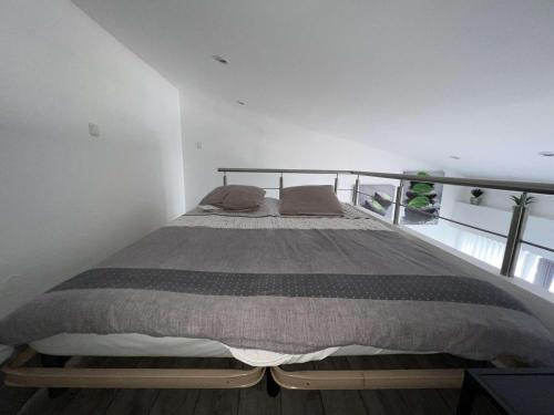 un lit dans une chambre blanche avec un cadre de lit dans l'établissement Studio mezzanine avec clim, piscine, proche plage, ascenseur, lave-linge - FR-1-702-27, au Cap d'Agde