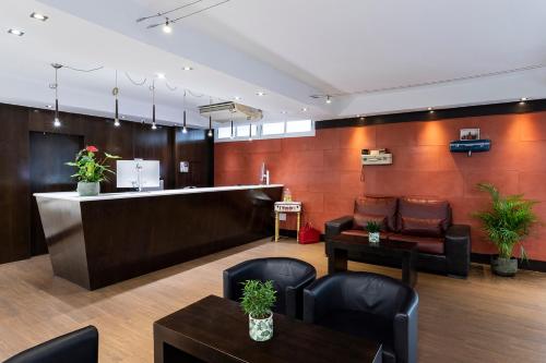 a waiting room with a counter and chairs and tables at Petit Palace Arturo Soria Alcalá in Madrid