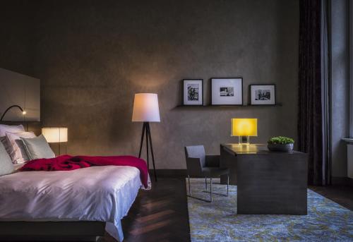 a bedroom with a bed and a desk with a lamp at SO/ Berlin Das Stue in Berlin
