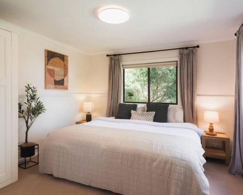 a bedroom with a large white bed and a window at The Acres of Tooborac Cottage in Tooborac