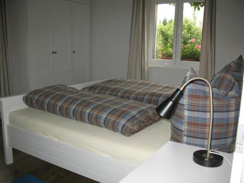 Una cama con una manta a cuadros y una lámpara. en Haus am Brunnen, en Titisee-Neustadt