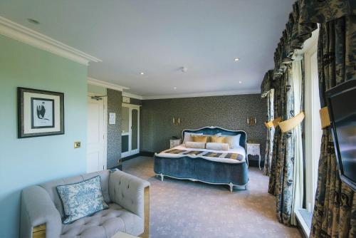 a bedroom with a blue bed and a couch at The Spa Hotel in Royal Tunbridge Wells