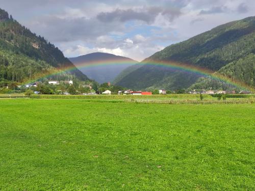 a rainbow in a field with a green field at Pension zum Mühlrad in Millstatt