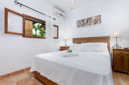 a bedroom with a white bed and a window at Cas Pati (Son Moja) in Santanyi