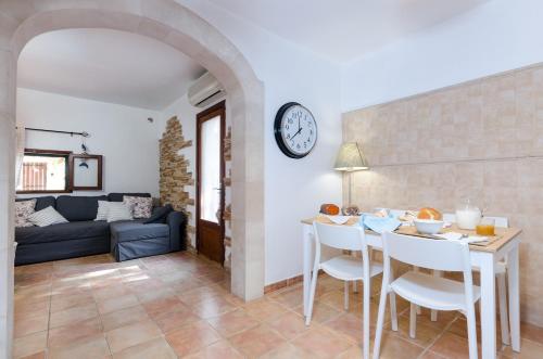 a living room with a table and a clock on the wall at Cas Pati (Son Moja) in Santanyi
