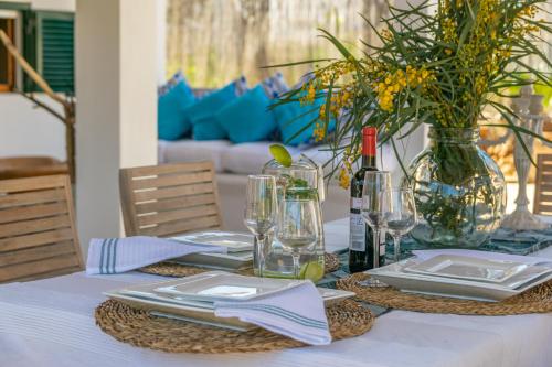 a table with plates and glasses and a vase with flowers at Cas Pati (Son Moja) in Santanyi