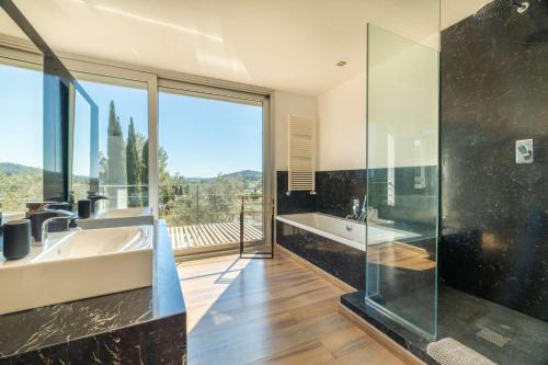 ein Badezimmer mit einer Badewanne und einem Waschbecken sowie ein großes Fenster in der Unterkunft Villa Vista in Pollença