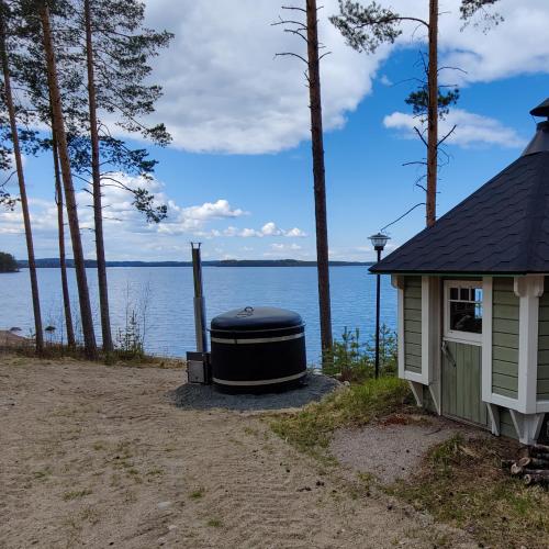 a house with a large barrel next to a body of water at Lake Cottage Jänisvaara in Kolinkylä