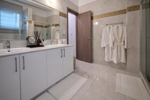 a white bathroom with a sink and a shower at Olymp Luxury Villa C - Seafront Elegance with Infinity Pool and Exclusive Lifestyle in Kissonerga