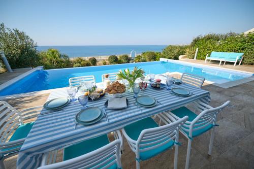 a blue table and chairs next to a swimming pool at Olymp Luxury Villa C - Seafront Elegance with Infinity Pool and Exclusive Lifestyle in Kissonerga