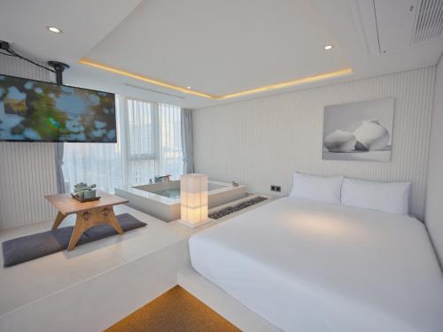 a white bedroom with a bed and a television at The Leap Seoul Sadang in Seoul