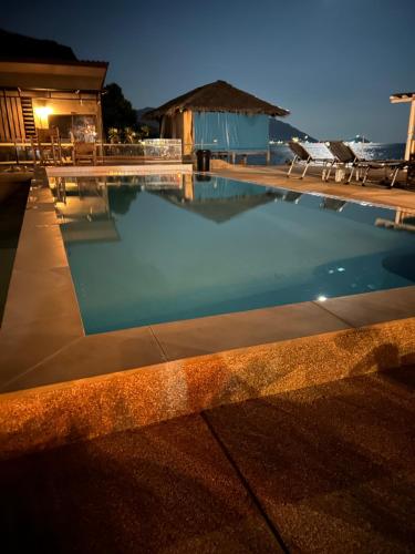 a swimming pool at night with chairs and a building at The Cosy Koh Phangan in Thongsala