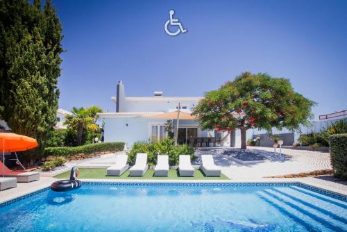 a swimming pool with chairs and a house at Horta's villa - private heatable Pool in Lagos